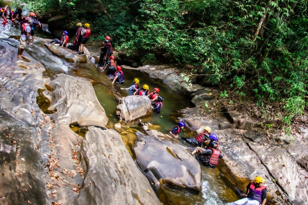 Adventurer sliding through a rainforest canyon pool on an Xclusive Adventures canyoning day in Kitulgala, Sri Lanka
